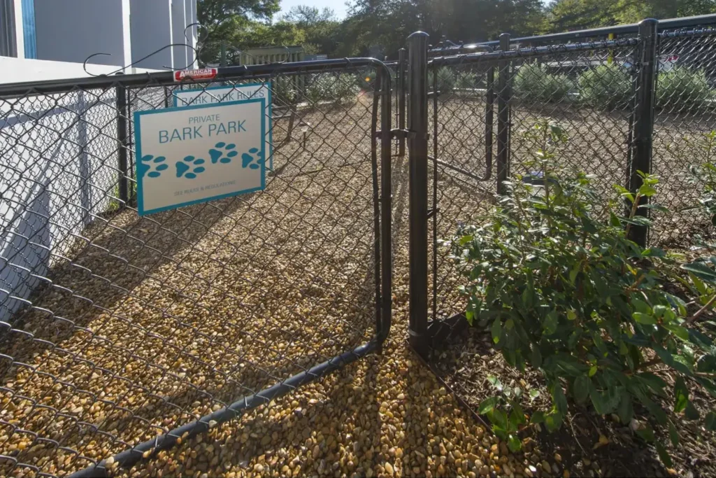 Fenced entrance to ‘Bark Park’, a dog park with a blue sign featuring a paw print design.