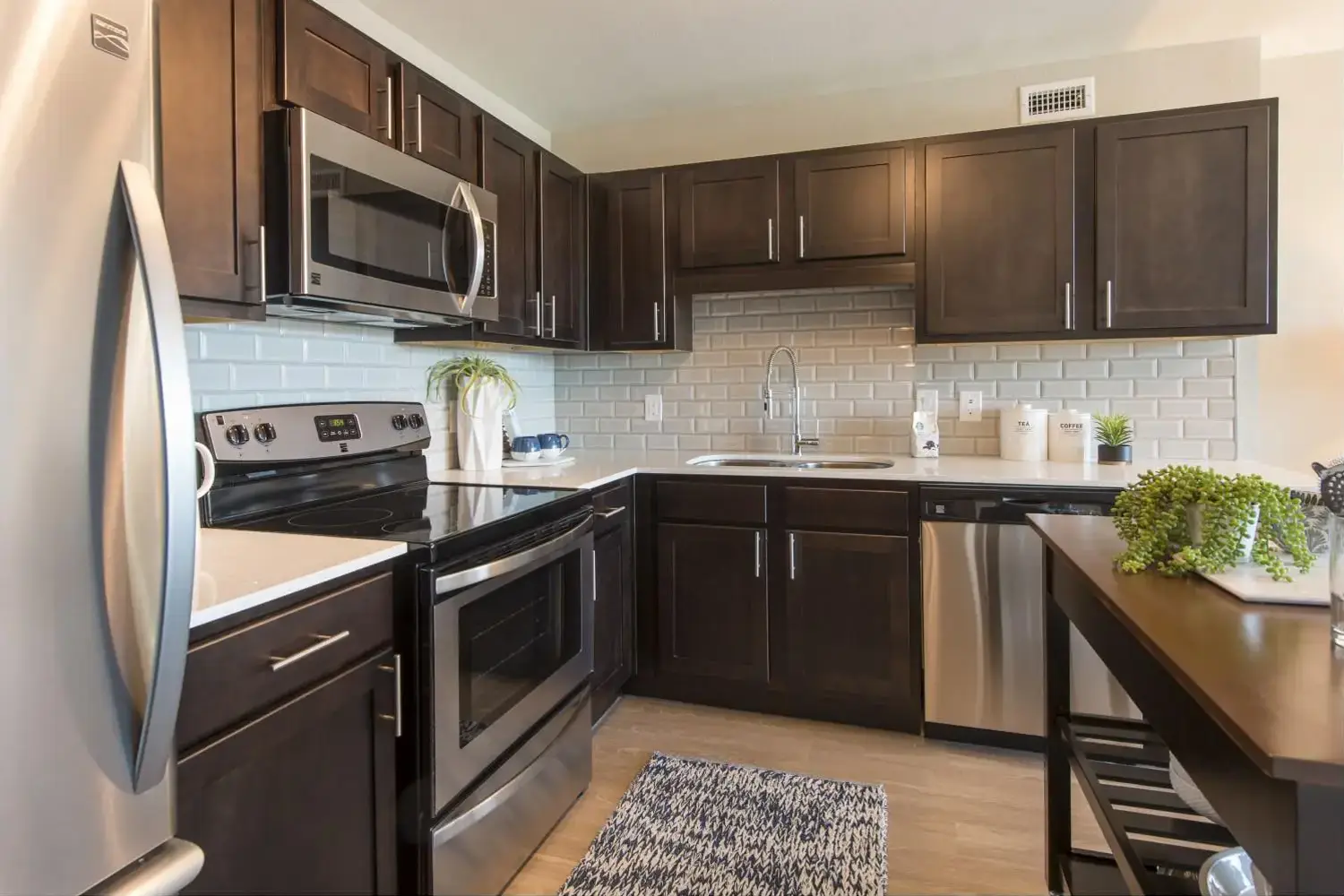 Modern kitchen with dark wood cabinets, stainless steel appliances, and light gray countertop.