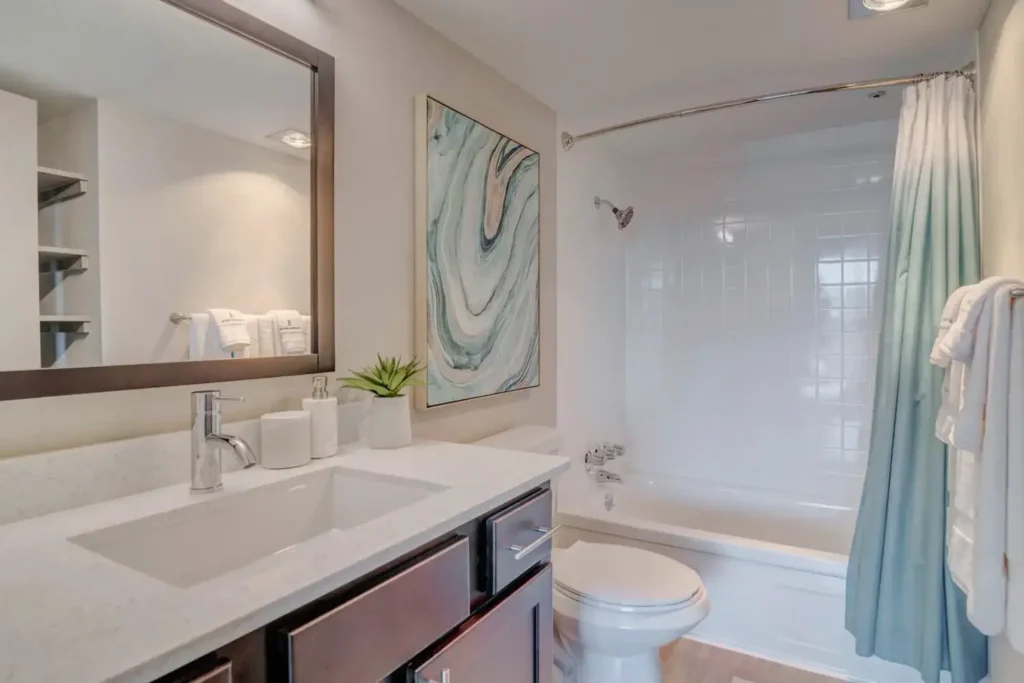 Modern bathroom with white fixtures and a green plant.