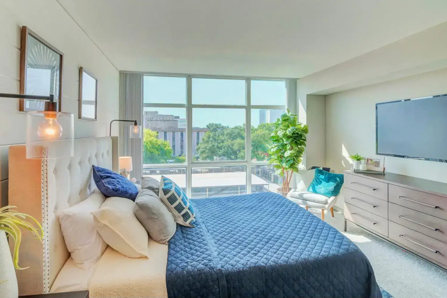 Modern bedroom with blue bedding and city skyline view.